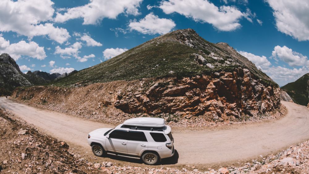 SUV driving on a rugged mountain road with scenic landscape, ideal for Sikkim road trip, adventure travel, and off-road tourism.